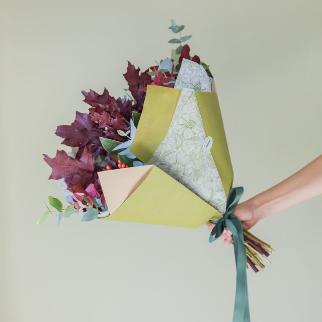 Embrulho kraft verde, papel floral verde e duplo laço verde-floresta.